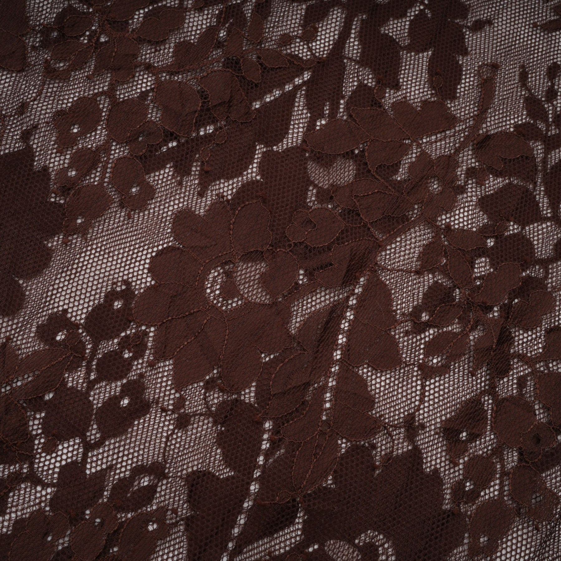 A brown flared midi dress made of chantilly lace named Sylvie hanging on a hanger against a plain background