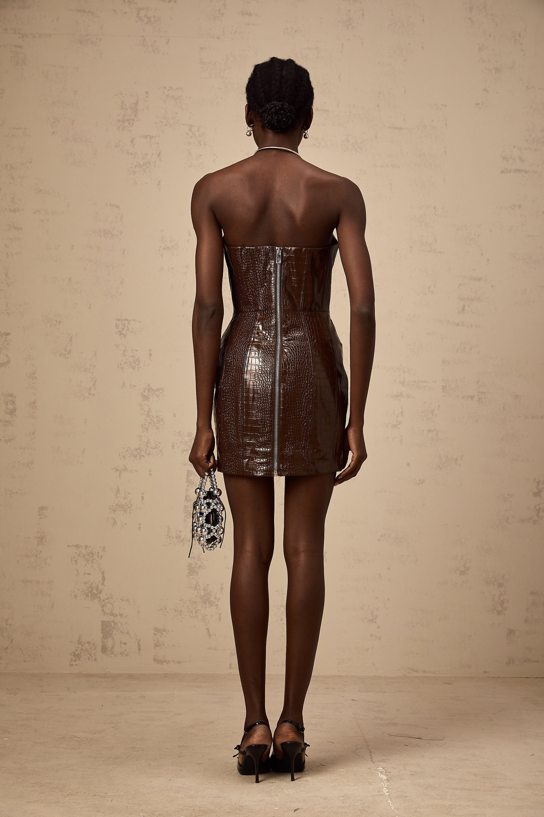 A brown mini dress made of textured leather with a short hemline and sleek design
