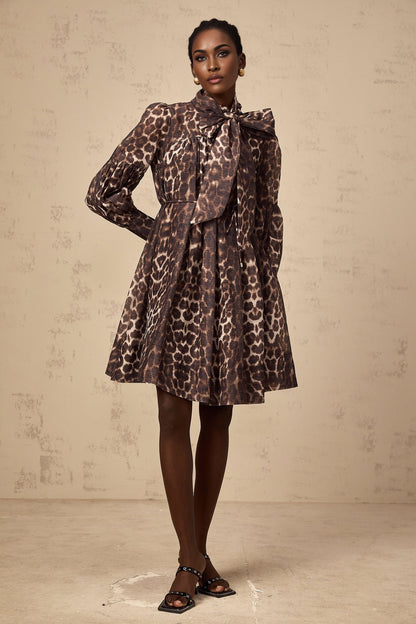 A brown mini dress with leopard print pattern featuring a large bowknot detail and a xylene inspired design