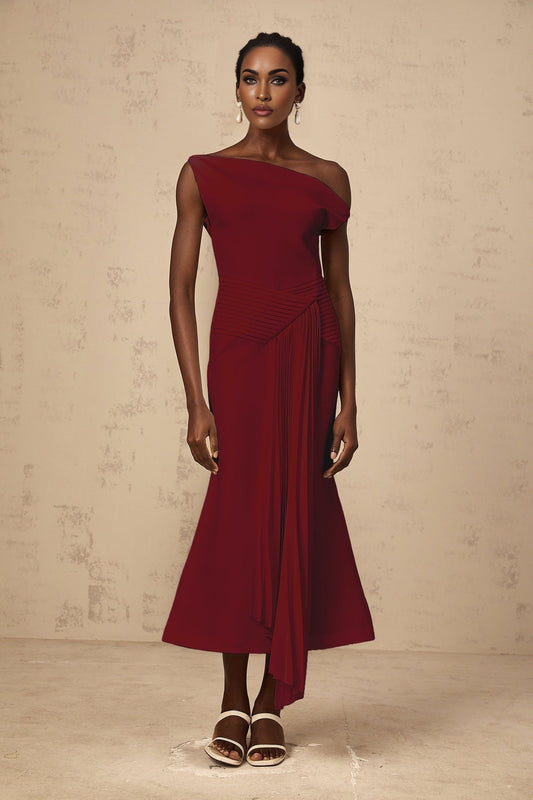 A burgundy asymmetrical midi dress with draped fabric detailing worn by a model standing against a plain background