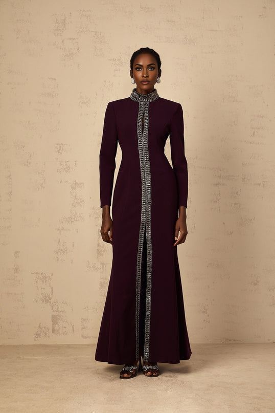 A burgundy floorlength maxi dress with a flared silhouette featuring embellished details and a design by Maelie