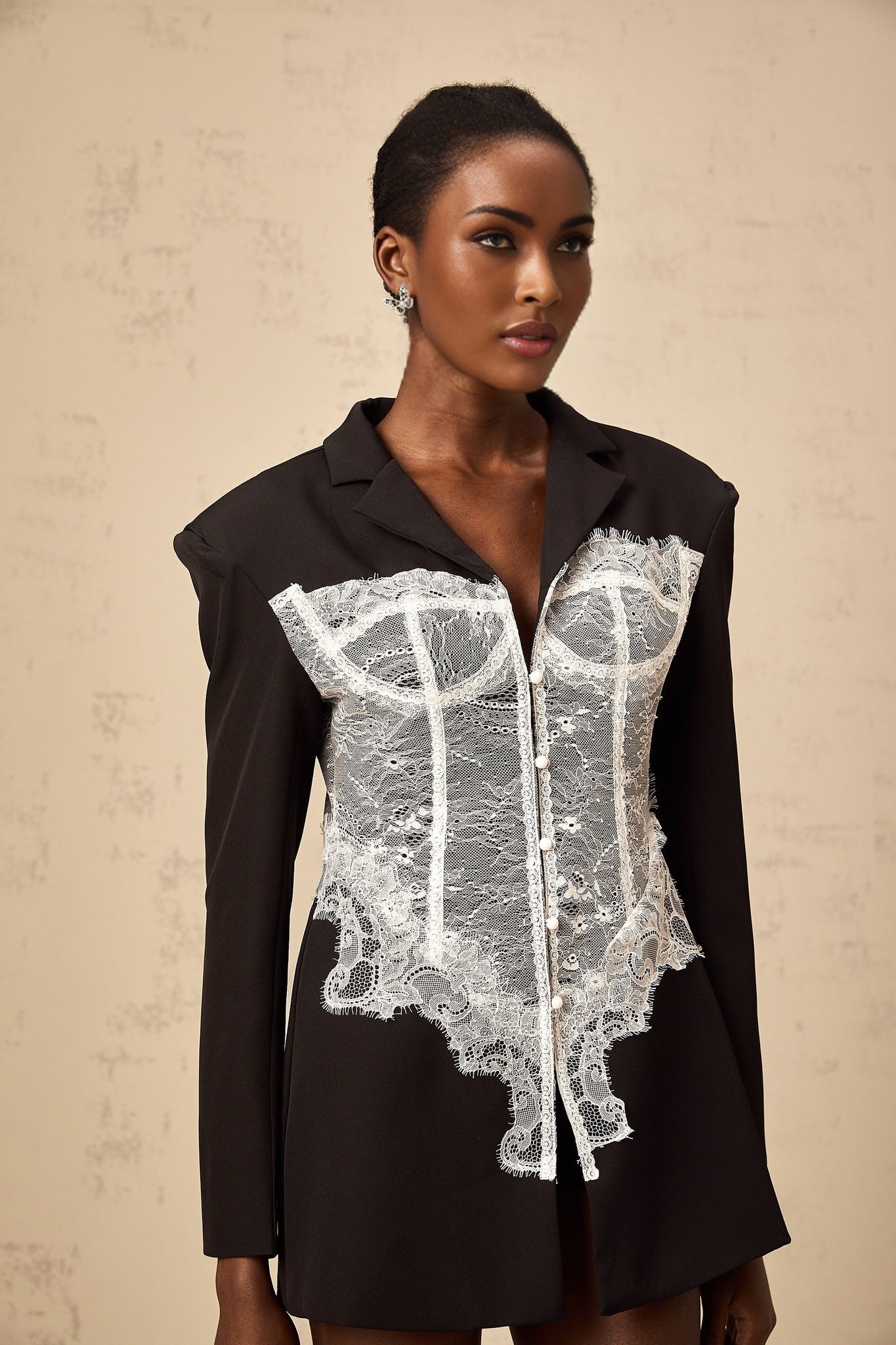 A colorblocked blazer featuring lace panels with a contrasting design combining solid fabric and delicate lace elements