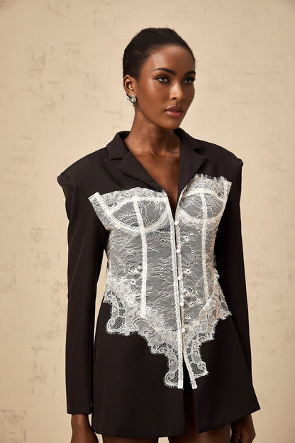 A colorblocked blazer featuring lace panels with a contrasting design combining solid fabric and delicate lace elements