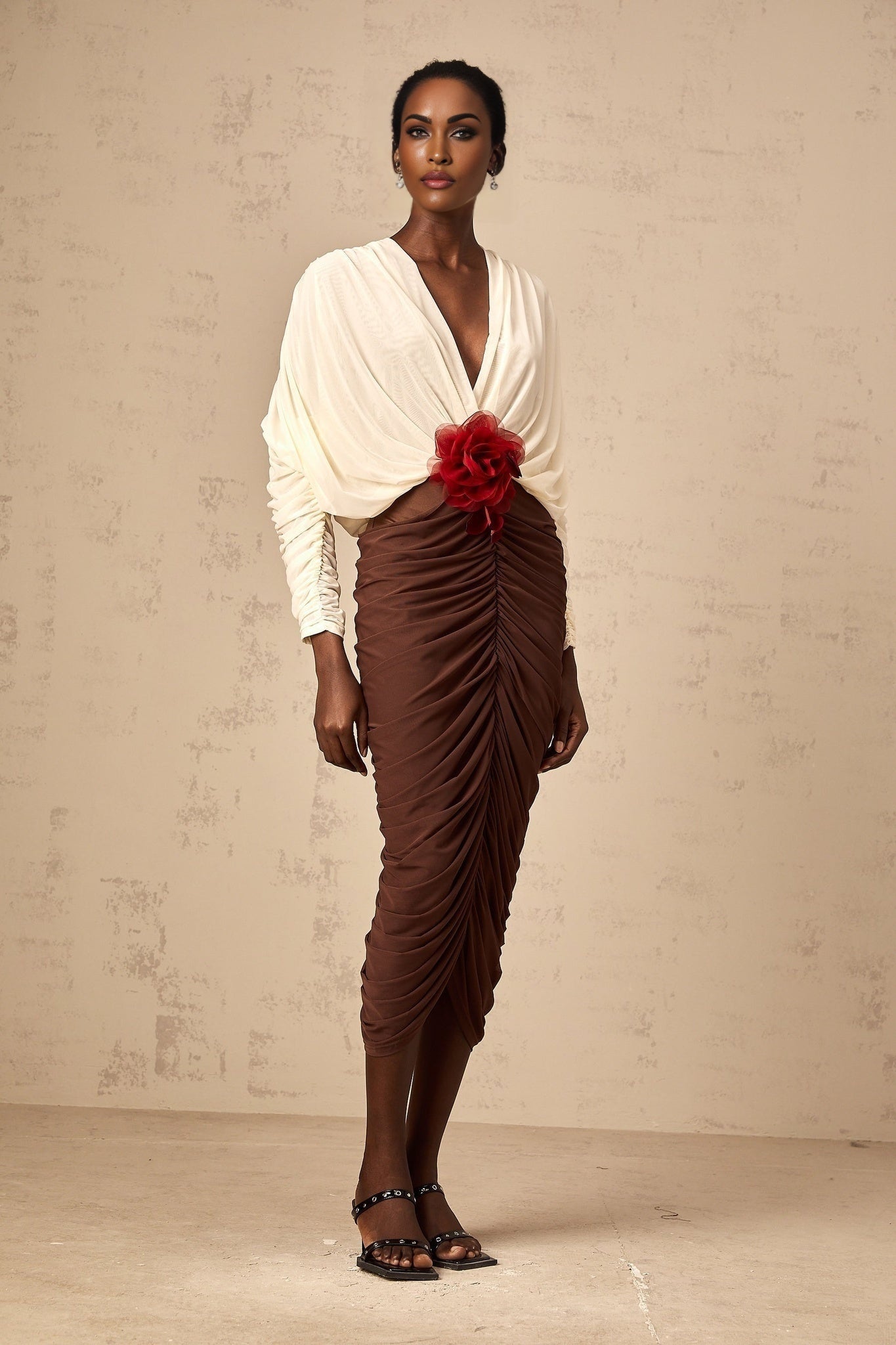 A colorful midi dress with ruched detailing featuring a colorblocked design and a decorative flower brooch accent