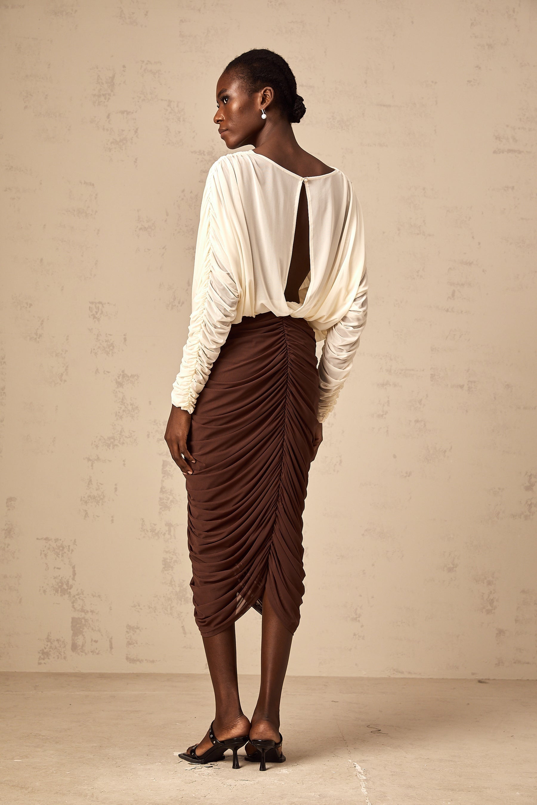 A colorful midi dress with ruched details featuring a prominent flower brooch and color blocking design named Leontine
