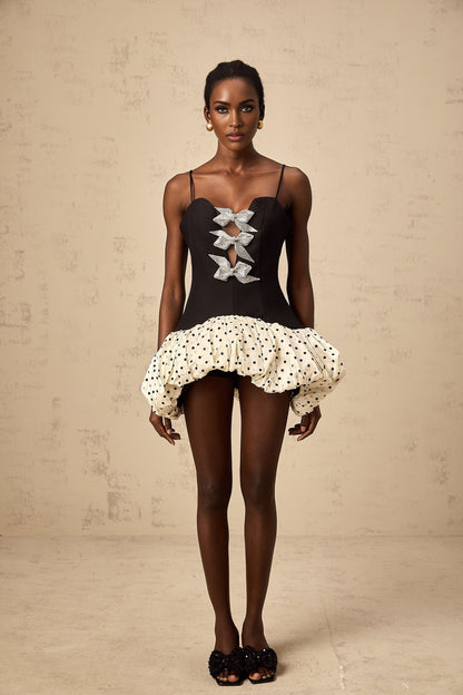 A colorful mini dress with a bow accent featuring a color block design and polka dot pattern