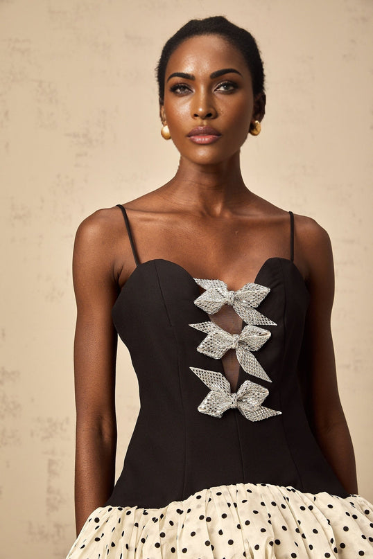 A colorful mini dress with polka dot pattern featuring color blocking and a decorative bow detail