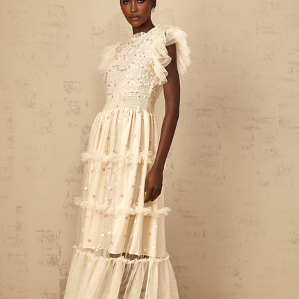 A cream white maxi dress with floral embroidery and tiered tulle skirt worn by a woman