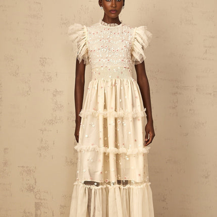A cream white maxi dress with floral embroidery and tiered tulle skirt worn by a woman
