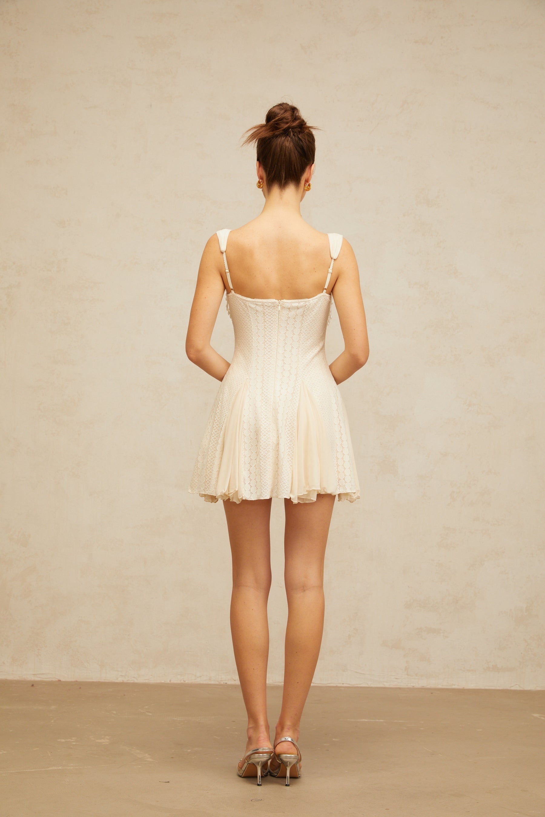 A creamwhite mini dress with a flared skirt and embellished details named Calliopee