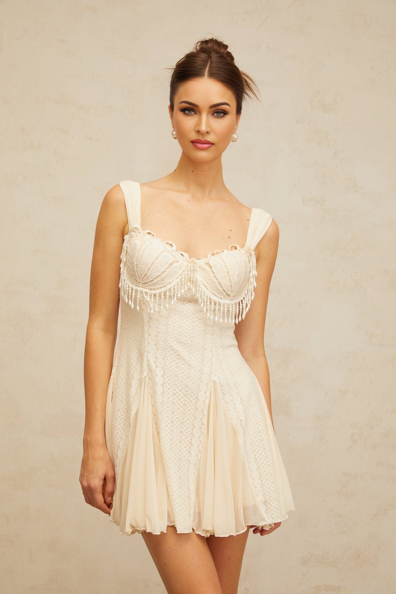 A creamwhite mini dress with a flared skirt and embellishments named Calliopee