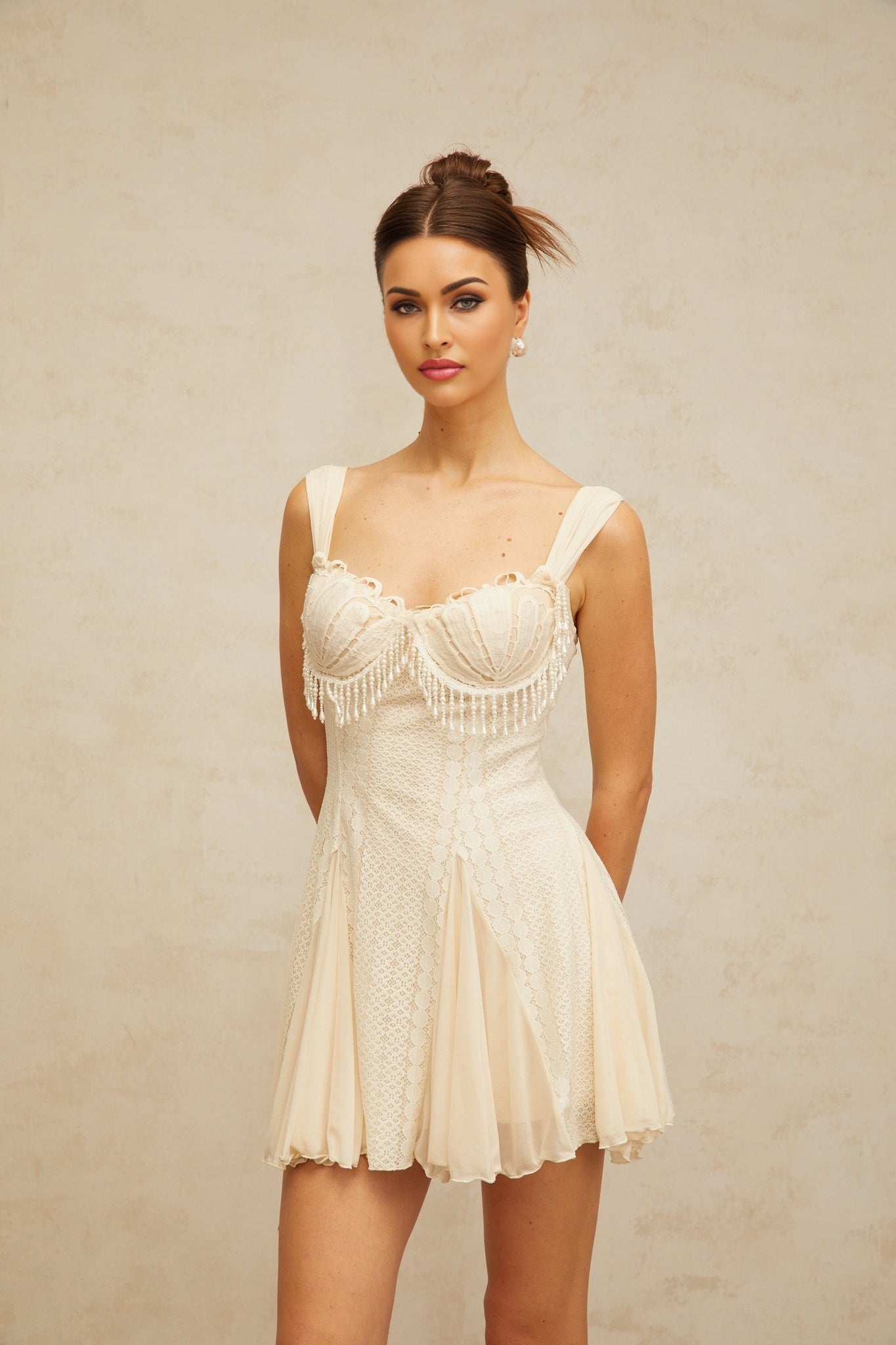 A creamwhite mini dress with flared skirt and embellished details named Calliopee