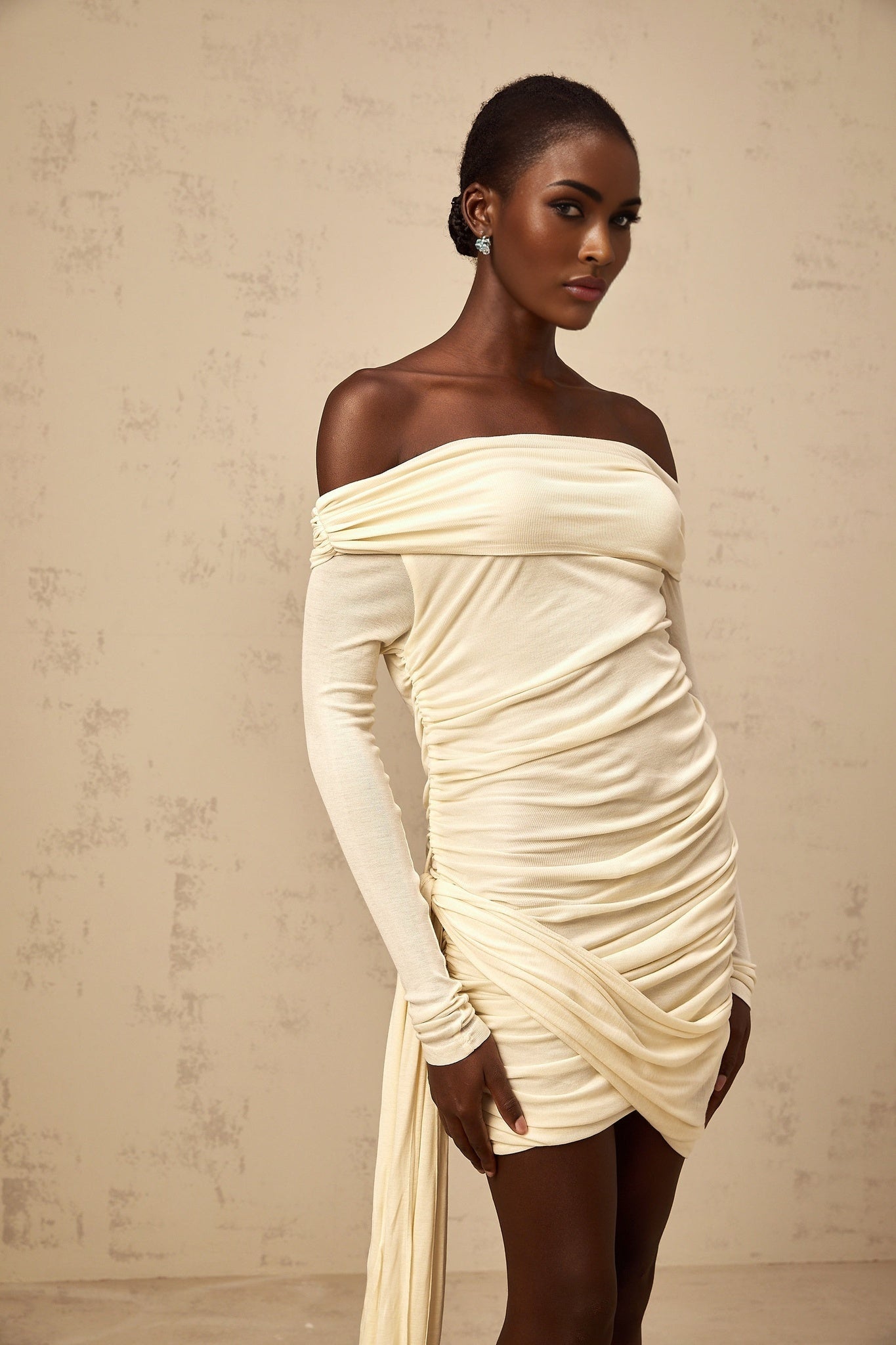 A creamwhite mini dress with ruched fabric and ribbon design details named Margaux