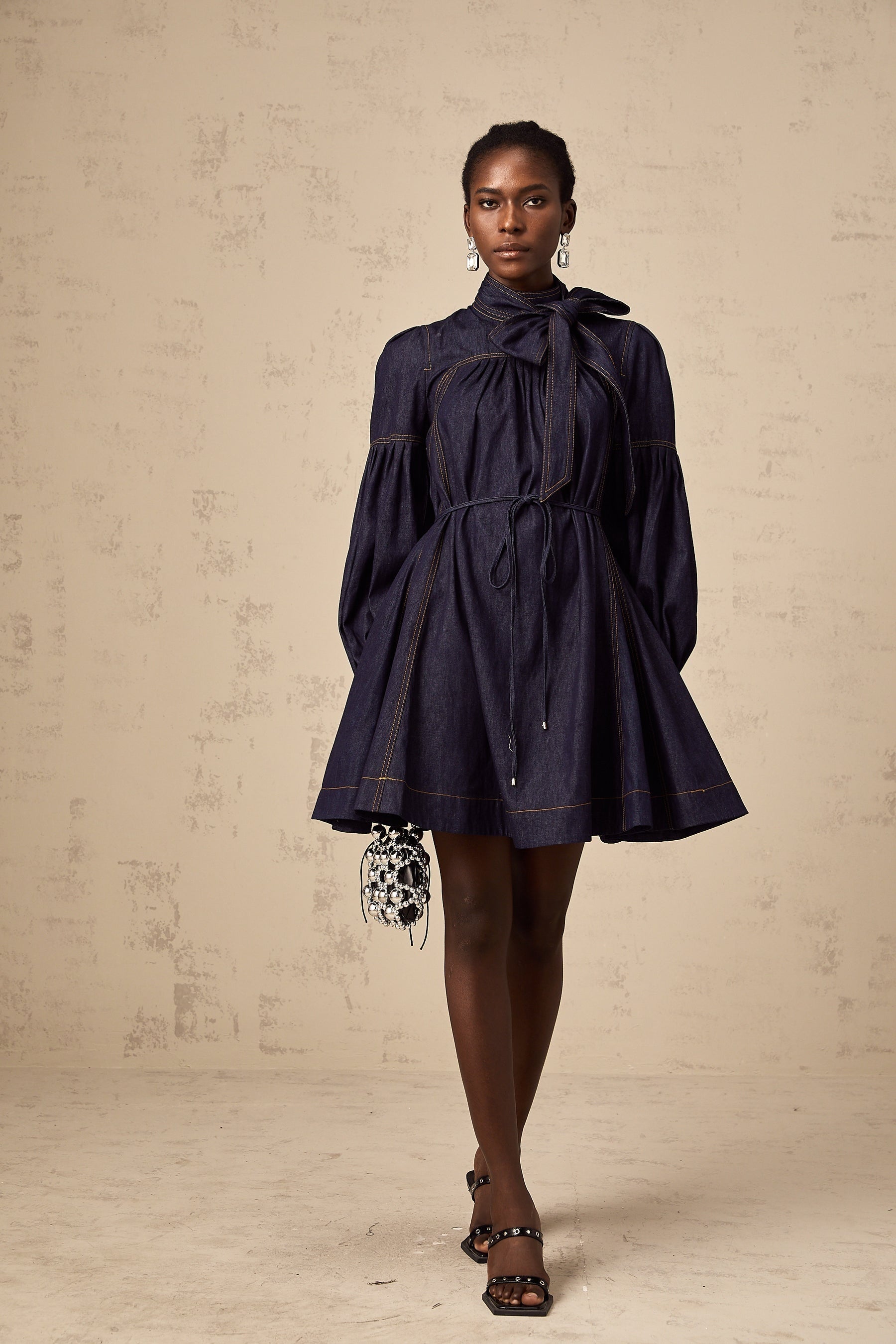 A dark blue denim mini dress with contrasting lightcolored stitching visible on the seams and edges