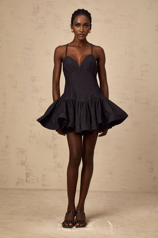 A dark blue denim mini dress with flounce detailing styled in a feminine design by Geneviève