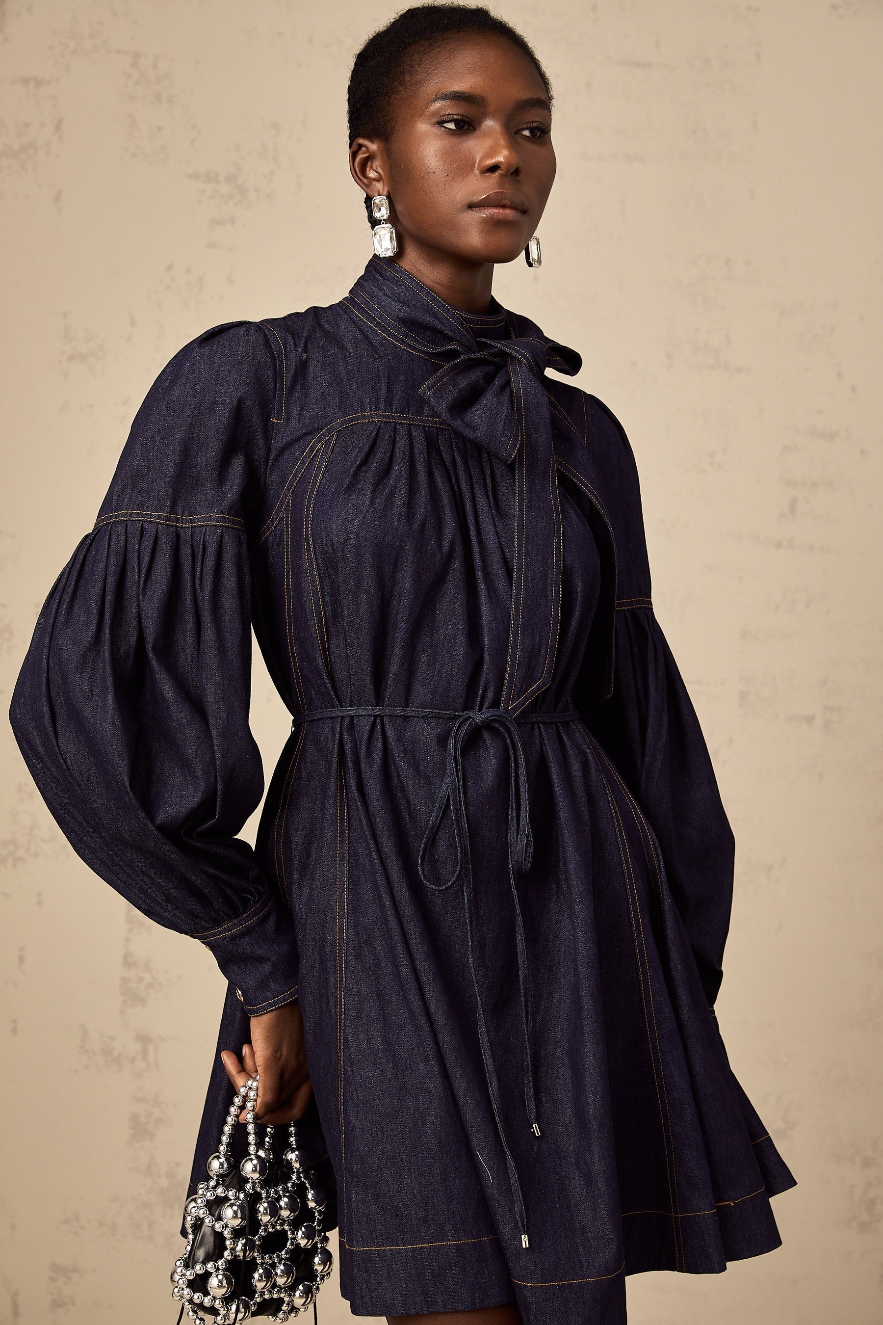 A dark blue denim mini dress with visible contrast stitching named Mirabel