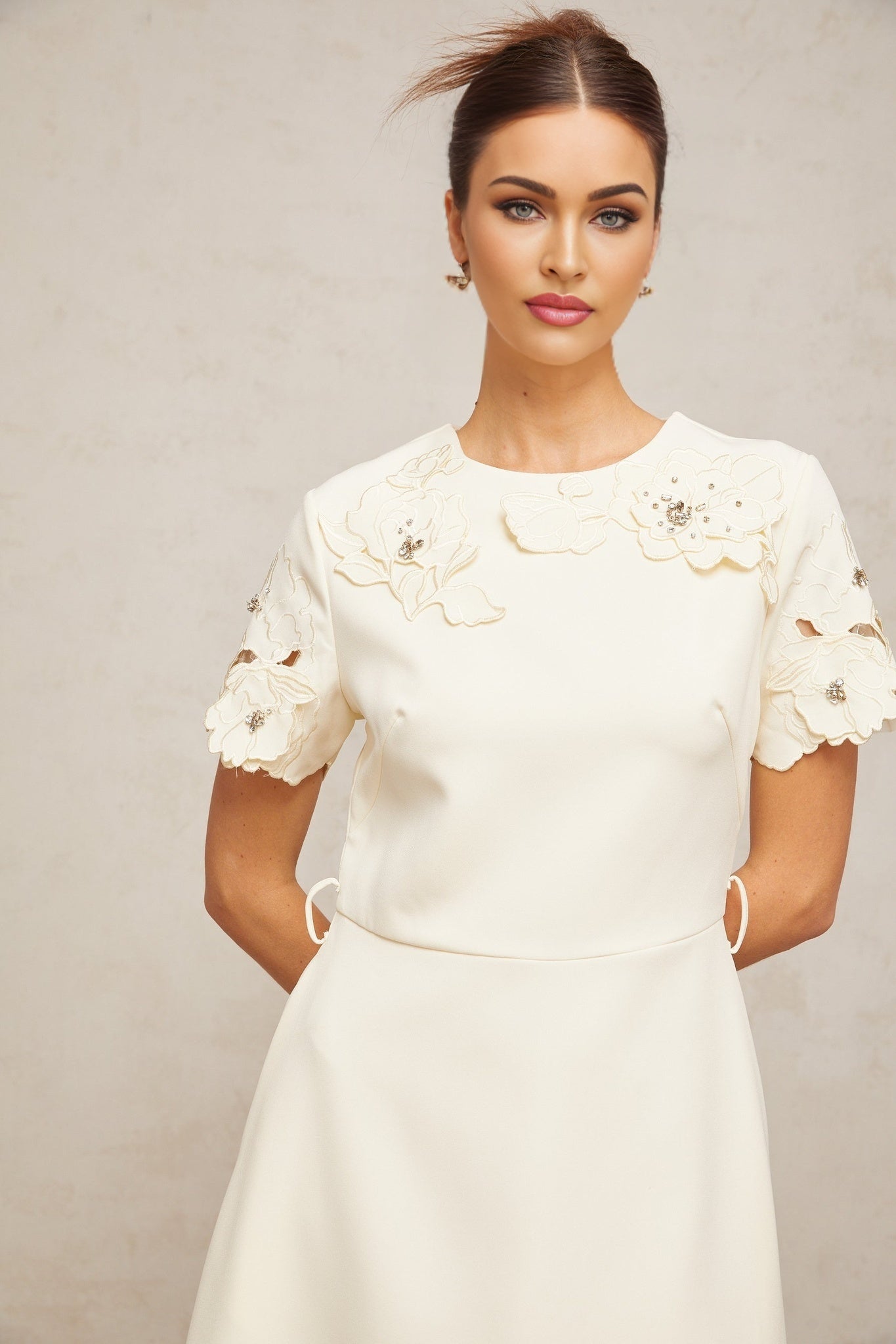 A feminine midi dress with a flared silhouette featuring neutral tones and floral appliqué details
