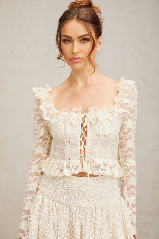 A feminine off white blouse with delicate floral lace pattern and ruffled details