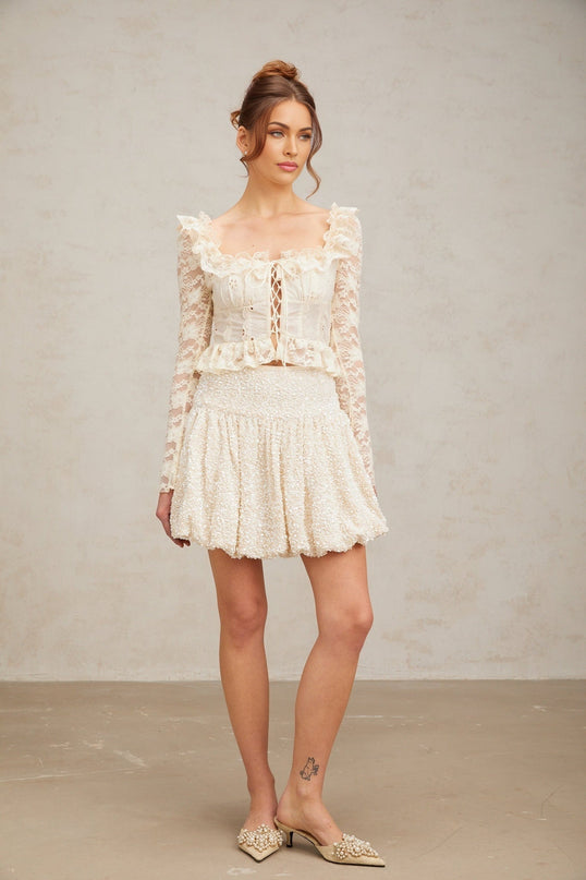 A feminine off white blouse with delicate floral lace pattern and ruffled details