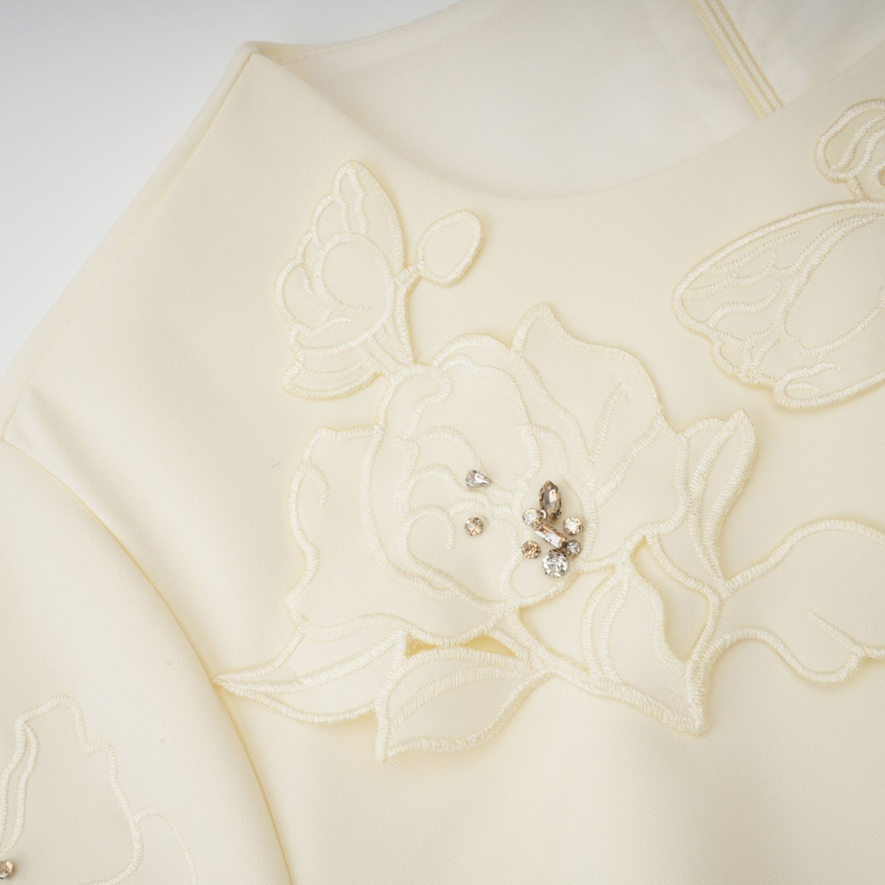 A flared midi dress in neutral tones featuring floral applique details with a predominantly orange color scheme