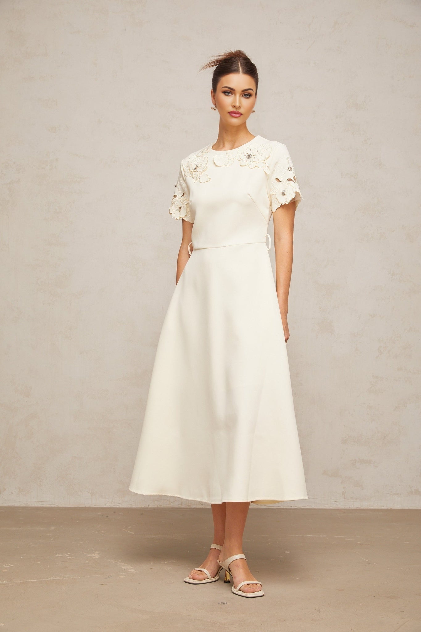 A flared midi dress in neutral tones featuring orange floral appliqué details