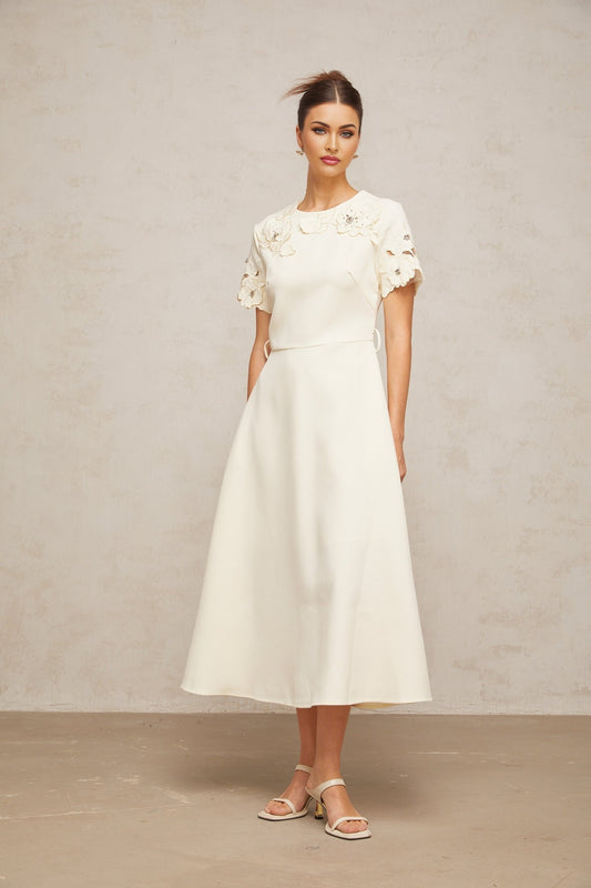 A flared midi dress in neutral tones featuring orange floral appliqué details