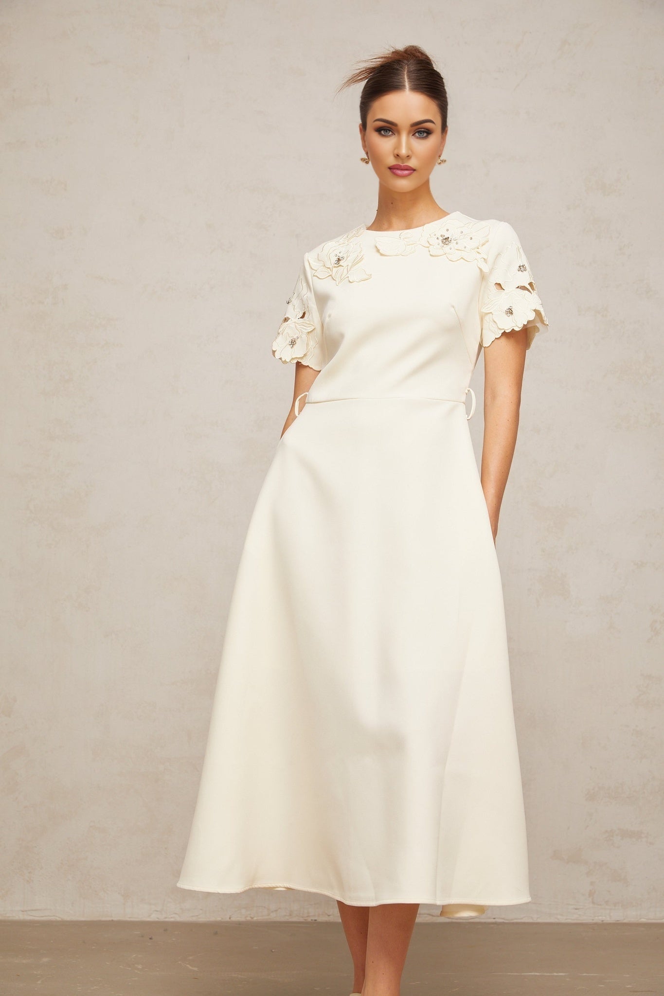 A flared midi dress in neutral tones featuring orange floral appliqués with a flowing silhouette