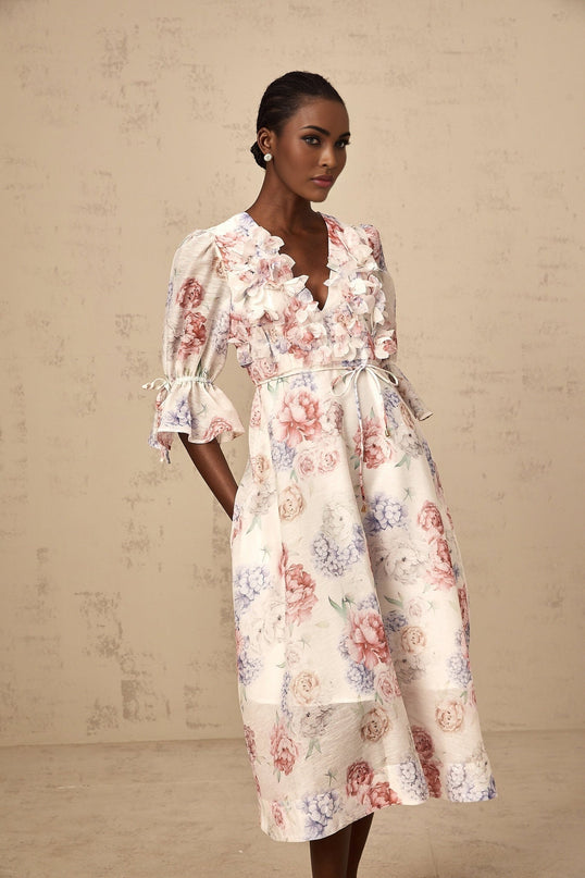 A floral midi dress with a 3d petal print pattern and tea colored background