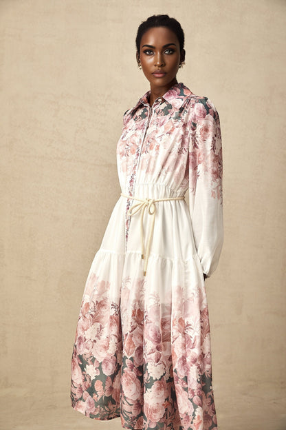A floral print midi dress with lantern sleeves named Carina featuring a colorful pattern on a light background and a flowing silhouette that falls to mid calf length