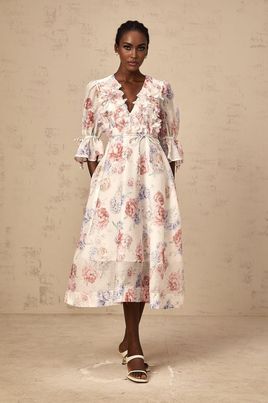 A floral print midi dress with threedimensional petal details featuring a vibrant pattern against a light background