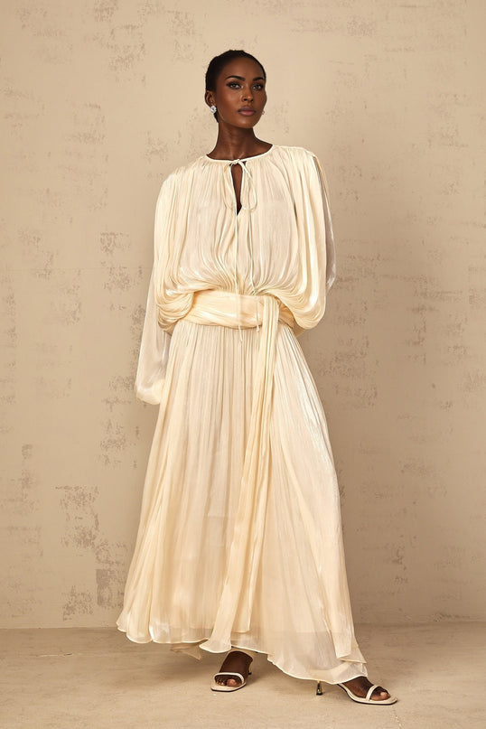 A flowing maxi dress with pleated ruffles in a neutral color featuring a long silhouette and feminine details