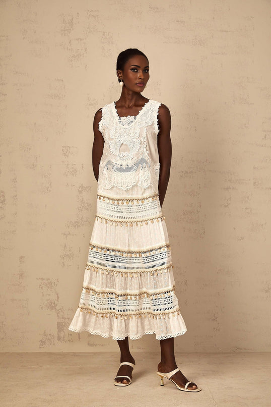 A flowy white midi skirt with shirred waistband and bohemian style details on a female model