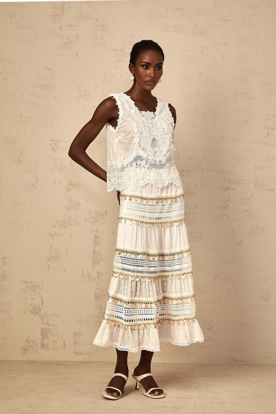 A flowy white midi skirt with shirred waistband and bohemianinspired design hanging on display