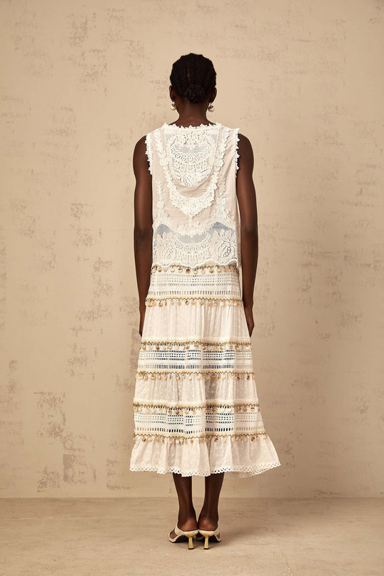 A flowy white midi skirt with shirred waistband and bohemianinspired design on a model