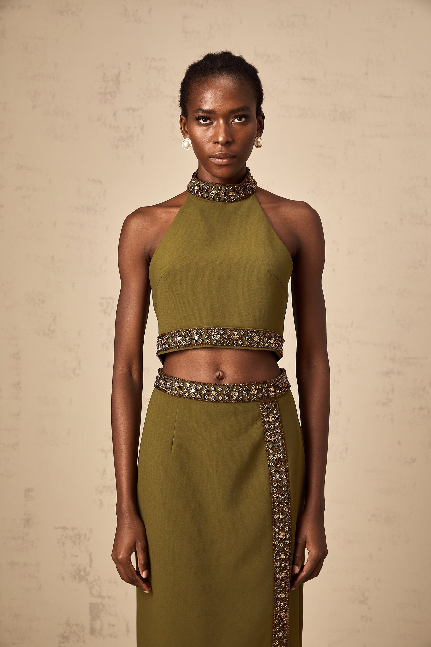 A green matching set featuring a top and skirt with daisyinspired beaded trim details