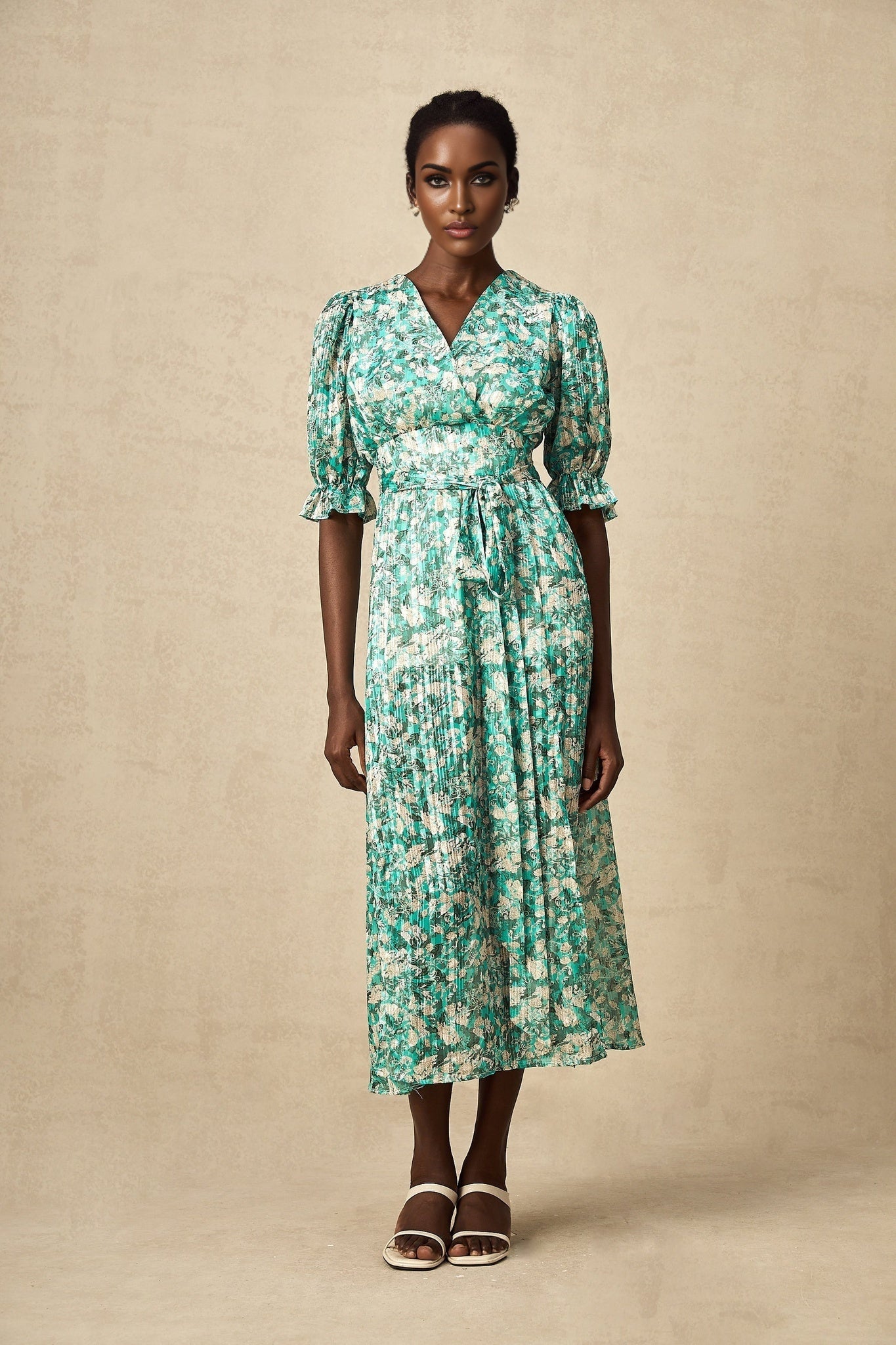 A green midi dress with a floral print pattern and a high slit featuring a feminine silhouette and flowing design