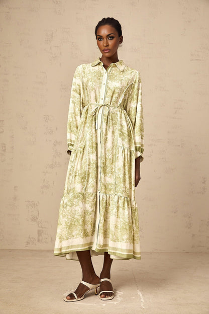 A green midi dress with a graphic print pattern called Adelaide worn by a model standing against a plain background