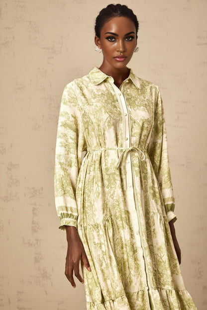 A green midi dress with a graphic print pattern featuring the Adélaïde design worn by a female model against a plain background