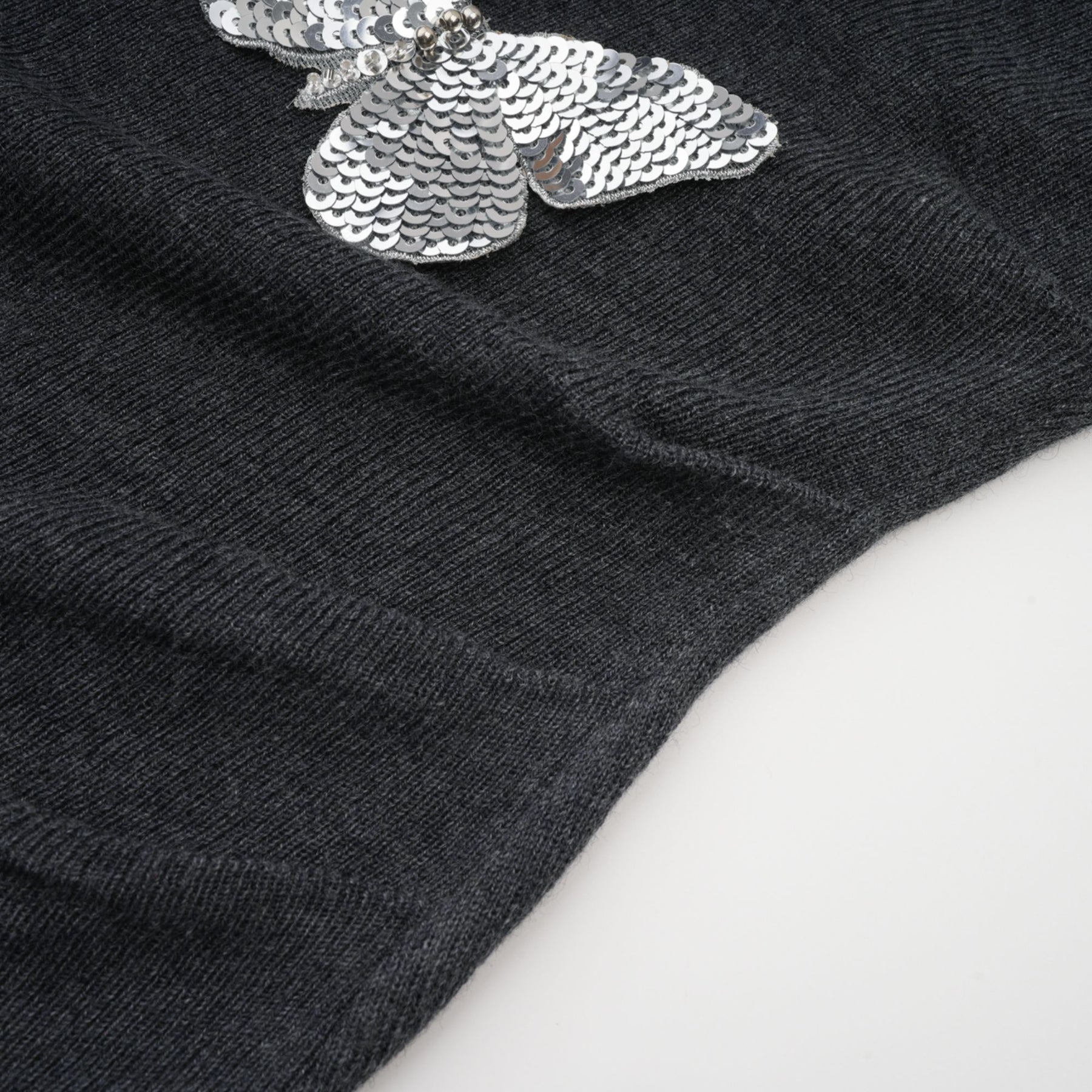 A grey cardigan with sequined butterfly designs adorning it