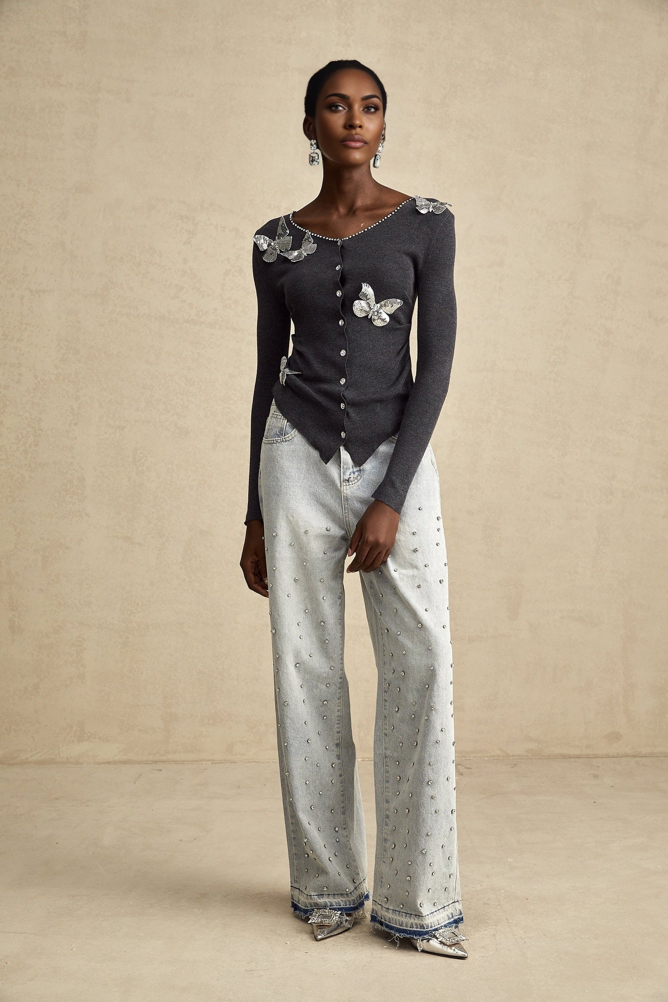 A grey cardigan with sequined butterfly designs adorning it