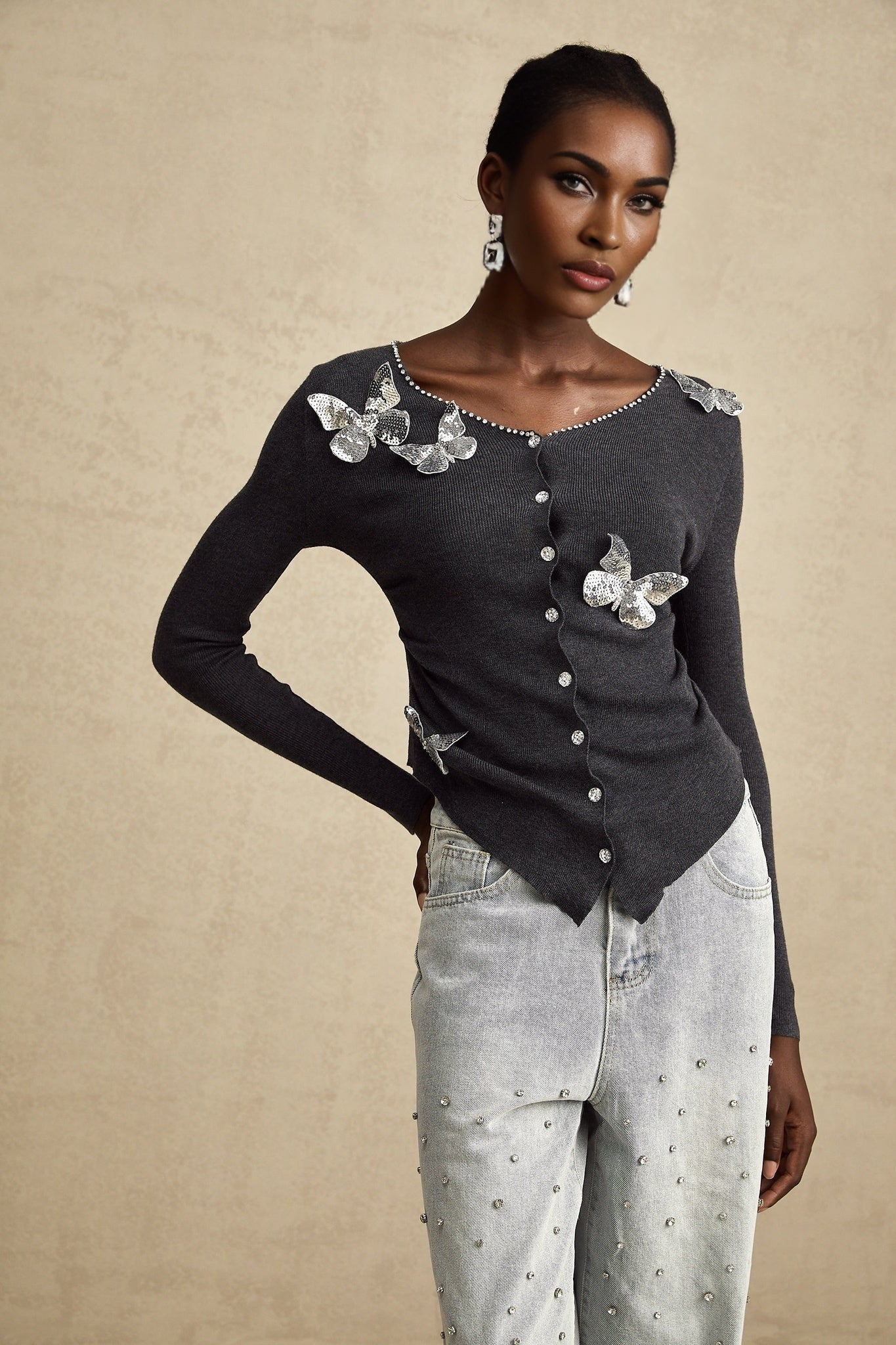 A grey cardigan with sequined butterfly designs adorning the fabric Anastasie brand