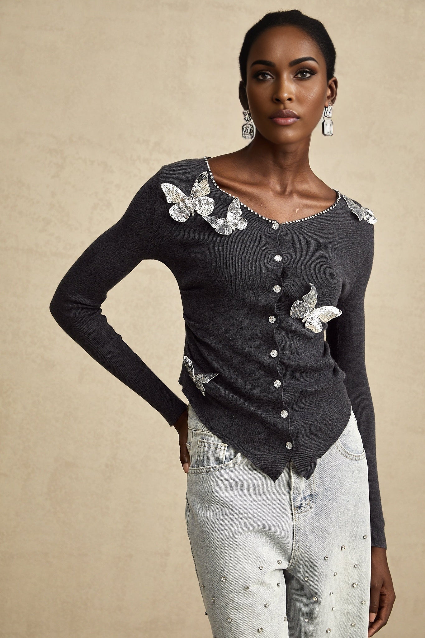 A grey cardigan with sequined butterfly designs adorning the fabric