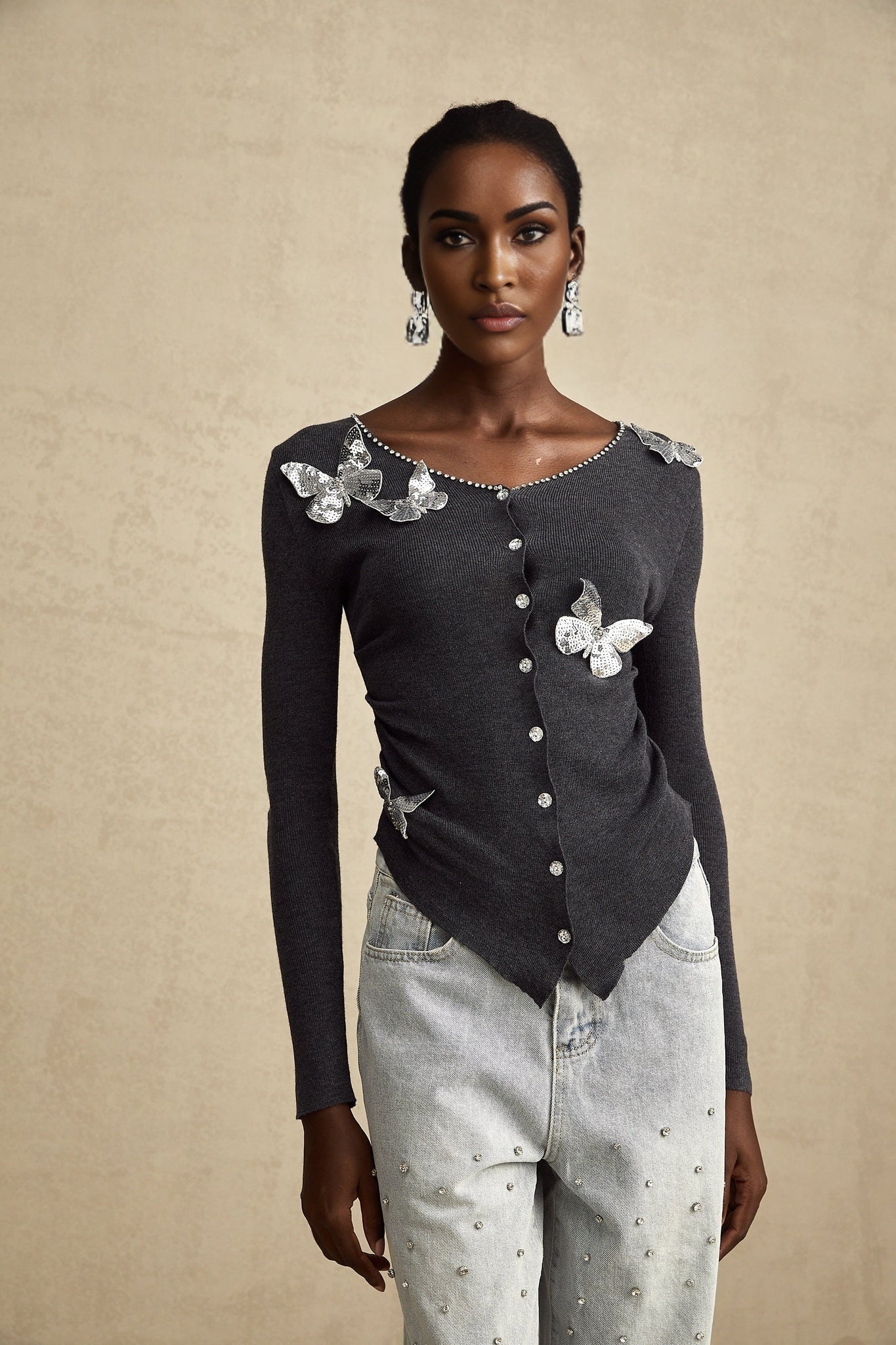 A grey cardigan with sequined butterfly designs scattered across it