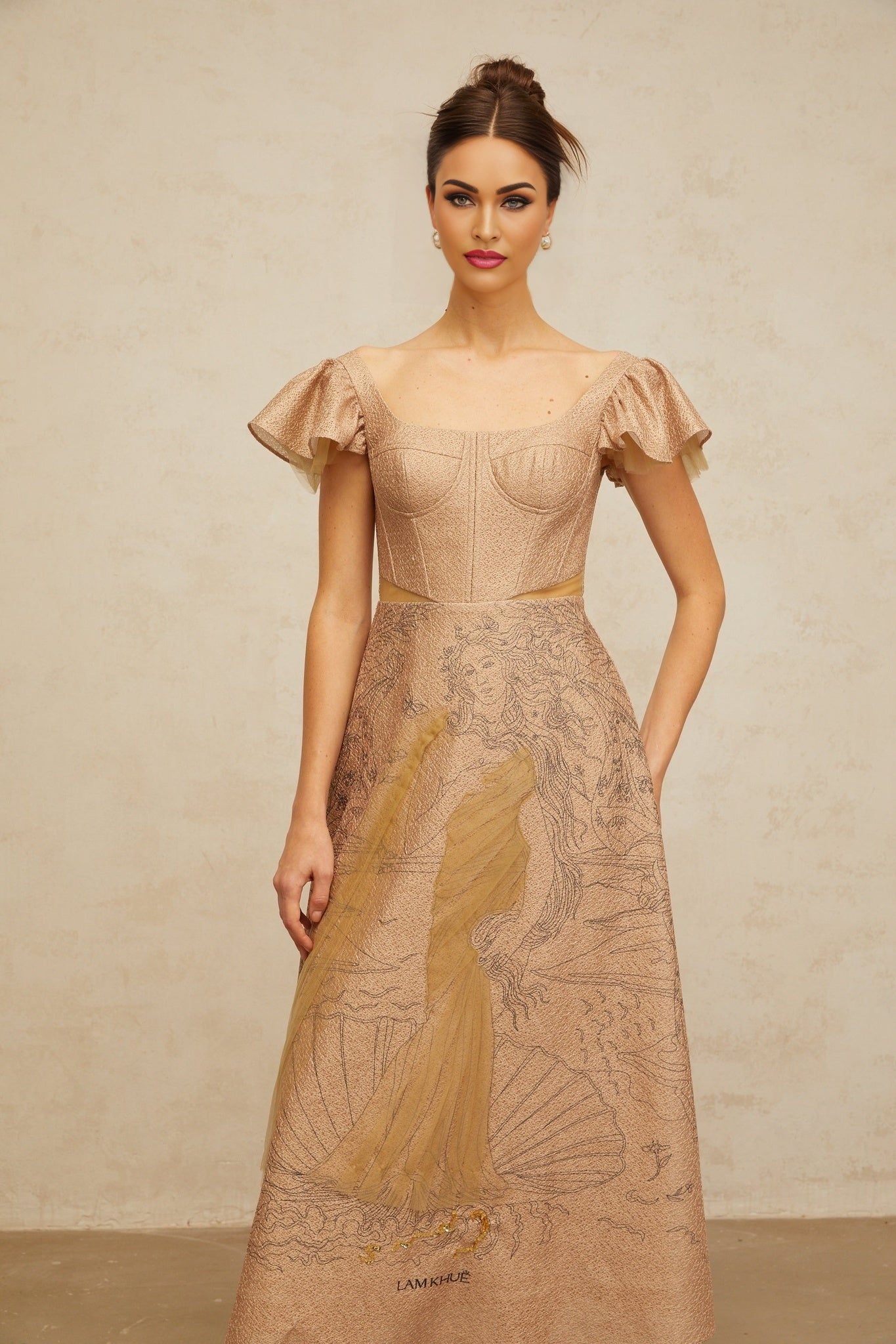 A khaki midi dress with a flared skirt featuring a graphic print pattern worn by a model standing against a plain background