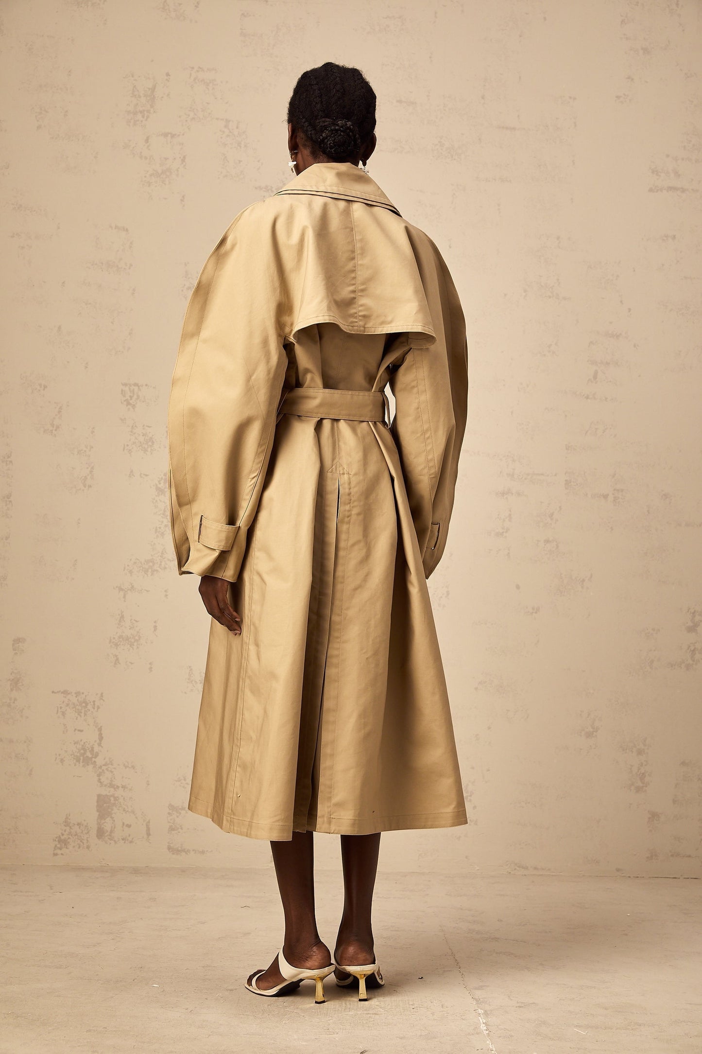 A khaki trench coat with curved sleeves modeled by someone named Jaden or in a style associated with Jaden