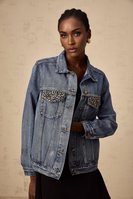 A light blue denim jacket adorned with sparkling rhinestones featuring a collar and button front closure