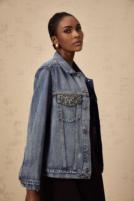 A light blue denim jacket adorned with sparkling rhinestones featuring a feminine design and a fitted silhouette