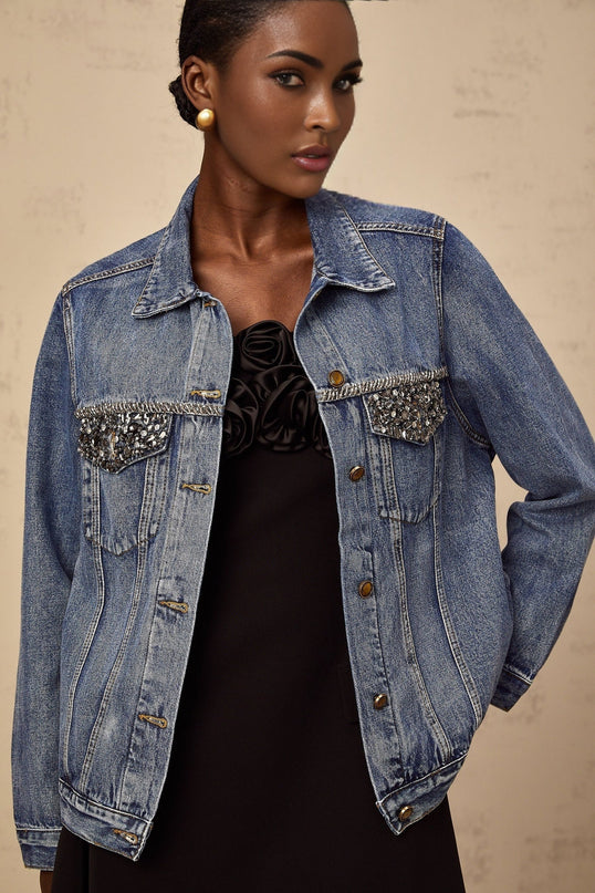 A light blue denim jacket adorned with sparkling rhinestones featuring a feminine design and stylish embellishments