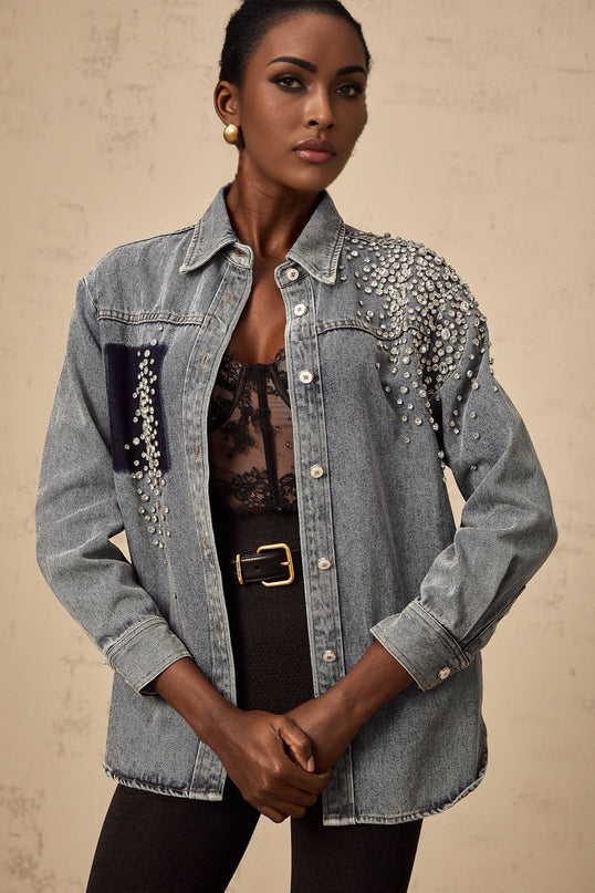 A light blue denim shirt adorned with sparkling rhinestones scattered across the fabric creating a glamorous and eye catching design