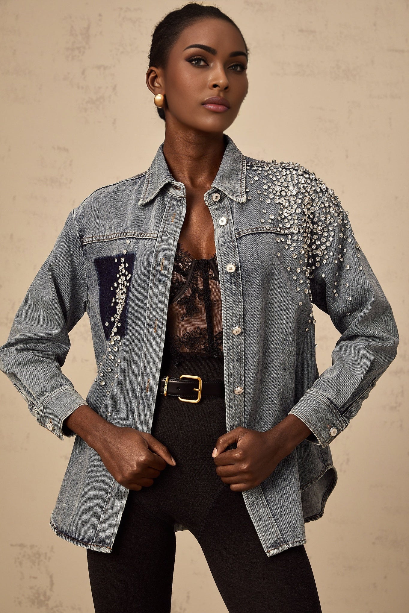 A light blue denim shirt with rhinestone embellishments scattered across the fabric featuring a classic collar and button front closure